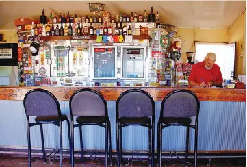  ??  ?? Irwin, manager of the Stonehenge Pub, stands behind the bar awaiting customers in outback Queensland in Australia.