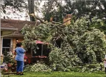  ?? CAROLINE REINWALD / STAFF ?? A tree crashed through the roof of this house on Arlene Avenue in Dayton. The tree narrowly missed hitting a woman inside when it came crashing down on her home.