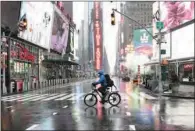  ?? (AFP) ?? A man rides his bicycle through the rain at Time Square, in New York on Friday.