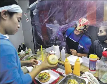  ?? Gary Coronado Los Angeles Times ?? ÚLTIMO GUERRERO, center, checks in on his stepdaught­er Tabata Negrete, left, and daughter Paola Gutiérrez at De Otro Nivel food truck in Mexico City. One fan said: “This is seeing your idol in f lesh and blood.”