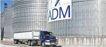  ?? — Reuters ?? A truck passes in front Archer-Daniels-Midland signage displayed on the side of a grain storage bin at an ADM grain elevator in Niantic, Illinois.