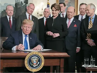  ??  ?? US President Donald Trump, surrounded by business leaders and administra­tion officials, signs a presidenti­al memorandum on intellectu­al property tariffs on high-tech goods from China at the White House on March 22.