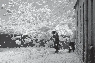  ?? MAL LANGSDON / REUTERS FRANCE ?? A family is caught in blowing sea foam on the Brittany coast after Storm Eleanor hit Saint-Guenole, France, on Wednesday.