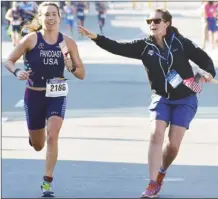  ?? Herald file photo ?? American duathlete Stephanie Pancoast accepts a flag from USA Triathlon official Meg Duncan during the ITU Multisport World Championsh­ips Festival in Penticton last summer.