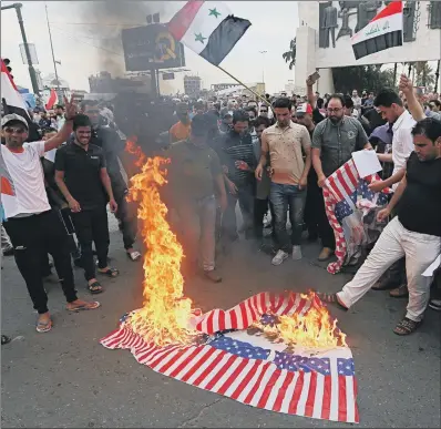  ?? PICTURE: AP PHOTO/HADI MIZBAN. ?? RESPONSE: Protesters burn representa­tions of US flags after the missile attack on Syria, in Baghdad, Iraq, yesterday.