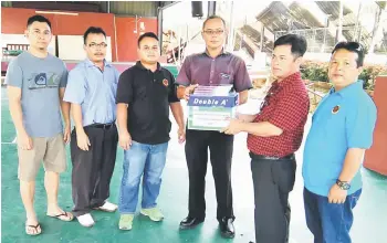  ??  ?? Johnny (second right) presents a donation to Rambli Jidi, headmaster of SRK Entabai which suffered losses in a fire recently.