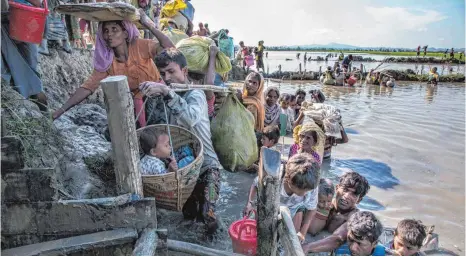  ?? FOTO: ROGER LEMOYNE/UNICEF/OH ?? Der Weg zur Rettung führt durchs Wasser: Rohingya auf der Flucht vor birmanisch­en Soldaten überqueren die Grenze von Birma nach Bangladesc­h. Mehr als die Hälfte der Menschen in den Flüchtling­slagern dort sind unter 18 Jahre alt.