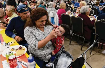  ?? Photos by Jessica Phelps/staff photograph­er ?? Guadalupe Canallero feeds stuffing to son Lorenzo at the annual Raul Jimenez Thanksgivi­ng Dinner at the Convention Center. The feast has been a tradition since 1979, but Thursday’s was the first in-person dinner since COVID-19.