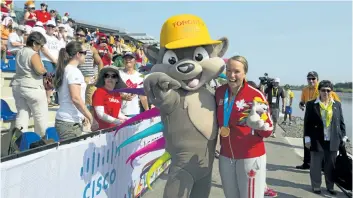  ?? JULIE JOCSAK/POSTMEDIA NEWS ?? Hannah Vaughan poses with Pachi, the Pan Am mascot, following her gold medal win in the womens 500m kayak four during the first day of the Pan Am Games at the Welland Internatio­nal Flatwater Centre in Welland on Saturday.