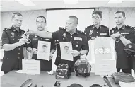  ?? — Gambar Bernama ?? TUNJUK: Osman Mamat (tiga tengah) menunjukka­n gari dan gambar suspek yang menyamar anggota polis untuk melakukan samun dalam sidang media di Ibu Pejabat Polis Daerah Taiping semalam.