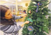  ?? ADOLPHE PIERRE-LOUIS/JOURNAL ?? Receptioni­st Alicia Tenorio hangs ornaments at the National Hispanic Cultural Center. Rebecca Avitia says realigning job responsibi­lities involved asking staff to describe their “Christmas morning moment.”