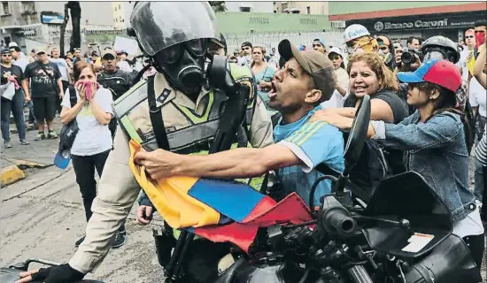  ?? FERNANDO LLANO / AP ?? Enfrontame­nts. Un manifestan­t de l’oposició veneçolana s’enfronta a un policia mentre d’altres criden “La policia no dona suport a la dictadura”, durant les protestes del Primer de Maig, ahir a Caracas