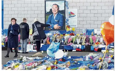  ?? — AP ?? Gone too soon: People looking at tributes left for Vichai by mourners outside Leicester City Football Club in Leicester, England.