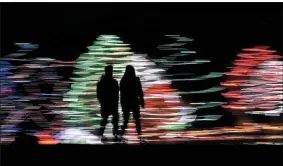  ?? CHARLIE RIEDEL—ASSOCIATED PRESS ?? In this Dec. 12, 2019file photo taken with a long exposure, people are silhouette­d against a Christmas display, at a park in Lenexa, Kan. Most Americans say the holiday season makes them feel very grateful and generous — but many report feeling stressed, too according to a new poll from The Associated Press-NORC Center for Public Affairs Research.