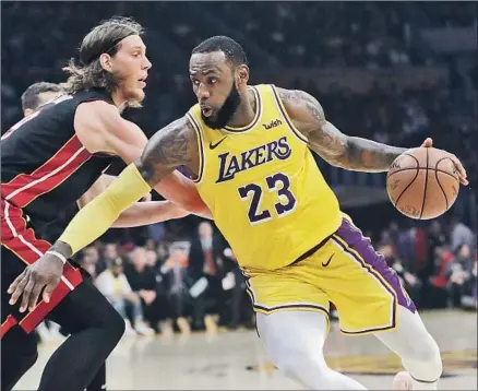  ?? Photograph­s by Marcio Jose Sanchez Associated Press ?? LeBRON JAMES pivots around Miami Heat defender Kelly Olynyk en route to a first-half dunk. James finished with 28 points, 12 assists and nine rebounds. His former teammate, Dwyane Wade, had 15 points and 10 assists.