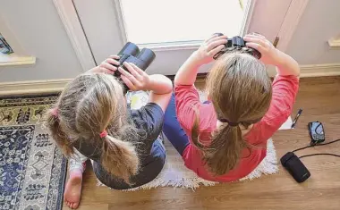  ?? Emily Tubbs/Macaulay Library/Cornell Lab of Ornitholog­y via AP ?? Two girls watch birds through a window with binoculars in Elm Grove, La., during the Great Backyard Bird Count in February 2022. About 385,000 people from 192 countries took part in the 2022 count, and their results have been used by scientists to study bird population­s worldwide.