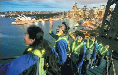  ?? JASON REED / REUTERS ?? Sightseers wear glowing vests as they look out to the Sydney Opera House from the Sydney Harbour Bridge on Thursday during a Chinese-language tour entitled Vivid Climb Mandarin. Sydney’s annual Vivid festival of light and sound will begin on May 26...