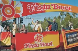  ?? MEGAN MENDOZA/THE REPUBLIC ?? Fiesta Bowl Volunteer Award Winners wave to the crowd from a float in the Fiesta Bowl Parade in Phoenix on Dec. 18.