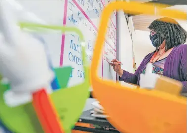  ?? PHOTOS BY GABRIELA CAMPOS/THE NEW MEXICAN ?? Jackie Gonzales, a kindergart­en teacher at Nava Elementary School, prepares her classroom for students returning next week. Gonzales will be Nava’s first teacher to return to in-person instructio­n, with the help of three aides.