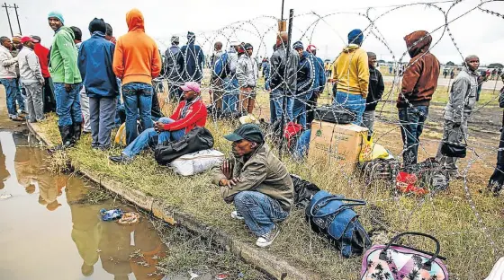  ??  ?? NO EASY RIDE: Striking Amplats miners wait to board buses provided by Amcu to go away for the Easter holidays