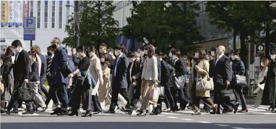  ?? The Yomiuri Shimbun ?? People in masks cross the road Monday in the Shinjuku district of Tokyo, amid commercial facilities that have temporaril­y closed under the state of emergency.