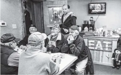  ?? THE ASSOCIATED PRESS ?? Farmer Brad Te Grootenhui­s, top, stands over morning regulars at the Boxcars Cafe in Hospers, Iowa. Te Grootenhui­s sells about 25,000 hogs a year and stands to lose hundreds of thousands of dollars in potential revenue if tariffs spark a backlash from...