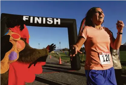  ?? Paul Chinn / The Chronicle 2013 ?? Dina Khaled crosses the finish line after running in the Napa Valley Turkey Trot 5K in 2013.