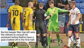  ??  ?? Burton keeper Ben Garratt asks the referee to consult his assistant before Bolton have a goal chalked off in the first half.