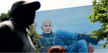  ?? AP ?? People walk past a billboard for the CNN television show Parts Unknownwit­h American celebrity chef Anthony Bourdain, in Atlanta, United States.