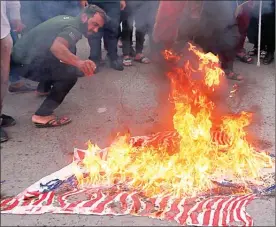  ?? HADI MIZBAN/The Associated Press ?? Protesters burn representa­tions of U.S. flags during a protest against the U.S.-led missile attack on Syria, in Tahrir Square, Baghdad, Iraq, Sunday.