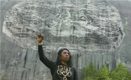  ?? JESSICA MCGOWAN/GETTY 2020 ?? Lahahuia Hanks holds up a fist in front of the Confederat­e carving at Stone Mountain Park during a Black Lives Matter protest in Stone Mountain, Georgia.