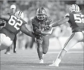  ?? Chris Gardner Getty Images ?? UTAH RUNNING BACK Zack Moss splits the defense against Brigham Young last month, when he rushed for 187 yards and a touchdown in 29 carries.