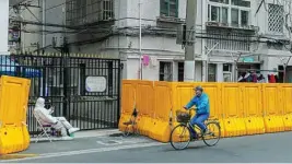  ?? EFE ?? Un hombre pasea en bicicleta junto a un barrio confinado de Shanghái