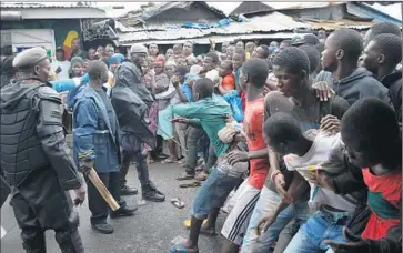  ?? Johnmoore Getty Images ?? in Monrovia’sWest Point slum await a food aid distributi­on during the government’s 11- day quarantine, a desperate attempt to contain the virus that was not endorsed by internatio­nal health officials.