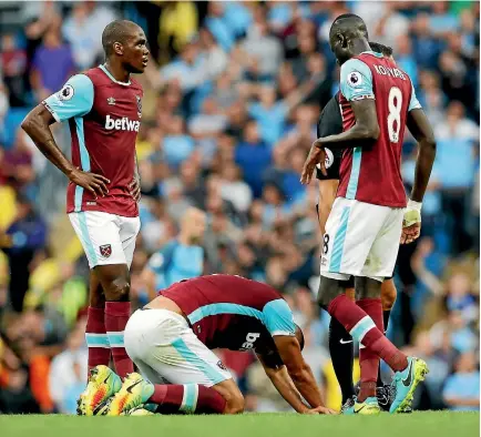  ?? PHOTO: REUTERS ?? West Ham’s Angelo Ogbonna and Cheikhou Kouyate look on as Winston Reid lies on the pitch after sustaining an injury.