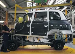  ?? REUTERS ?? The body of a TX4 is lowered onto its chassis on the production line at the London Taxi Company in