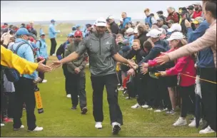  ?? The Associated Press ?? FAN CONTACT: Dustin Johnson of the United States touches hands with spectators Wednesday as he walks to the 17th tee during a practice round ahead of the start of the British Open at Royal Portrush in Northern Ireland. The British Open starts today.