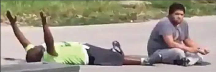  ??  ?? Appeal for calm: A still from a video shows Charles Kinsey lying on the ground with his arms in the air and his autistic patient sitting at his feet shortly before police opened fire