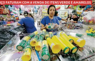  ??  ?? Funcionári­a de loja na região da rua 25 de Março repõe estoque dos produtos vendidos nos protestos contra Dilma; além de itens da Copa, vendedores encomendar­am faixas presidenci­ais