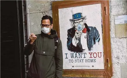  ?? AFP PIC ?? A man wearing a face mask posing with a poster by artist TVBoy featuring Uncle Sam that reads ‘I want you to stay home’ in Barcelona, Spain, on Saturday.
