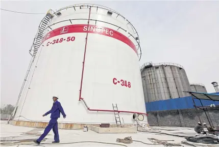  ?? REUTERS ?? An employee walks past oil tanks at a Sinopec refinery in Wuhan, Hubei province, China.