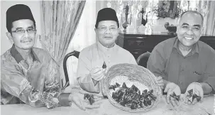  ?? — Gambar Bernama ?? LEBIH BERKHASIAT: Ahmad (tengah) menunjukka­n dodol yang dihasil menggunaka­n campuran santan kelapa dan santan sawit ketika ditemui pemberita selepas Majlis Rumah Terbuka Aidilfitri di rumahnya di Jasin, kelmarin. Turut hadir Ahmad Kushairi (kanan).