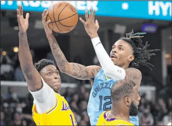  ?? Nikki Boertman The Associated Press ?? Grizzlies guard Ja Morant soars to the basket between Lakers forwards Stanley Johnson and Lebron James in Memphis’ 104-99 win Wednesday at Fedexforum.