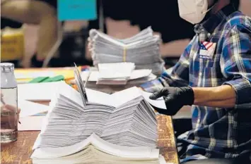  ?? CHANG W. LEE/THE NEW YORK TIMES ?? After Joe Biden won Wisconsin by barely 20,682 votes, Republican­s began making evidence-free claims of fraudulent votes cast across the state. Above, an election worker processes ballots last year in Milwaukee.