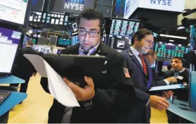  ?? Richard Drew / Associated Press ?? Traders Michael Capolino (left) and Benjamin Tuchman work on the floor of the New York Stock Exchange, which had a wild week.