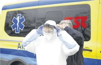  ?? NURIA SOLER ?? Una profesiona­l sanitaria del Royo Villanova se coloca el equipo de protección, con mascarilla de filtro.