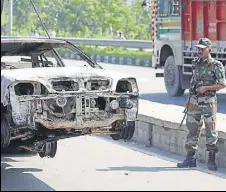  ?? REUTERS ?? A soldier looks at a car damaged in arson, a day after the August 25 violence in Panchkula.