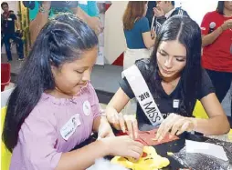  ??  ?? Miss Philippine­s Universe 2019 Gazini Ganados (with a child during the World Smile Day celebratio­n) has yet to create and name her own Miss U walk