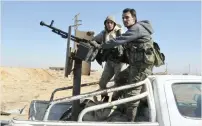  ?? — AFP ?? Syrian government forces stand in the back of an armed vehicle as they approach the strategic Jihar oil fields on the eastern outskirts of Homs on Tuesday.