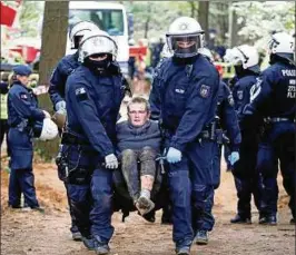  ??  ?? Einsatzkrä­fte der Polizei tragen eine Umweltakti­vistin aus einem Waldstück des Hambacher Forsts. Foto: Wolfgang Rattay/reuters